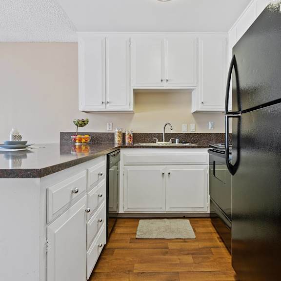 a kitchen with white cabinets and a black refrigerator at terramonte apartment homes, pomona