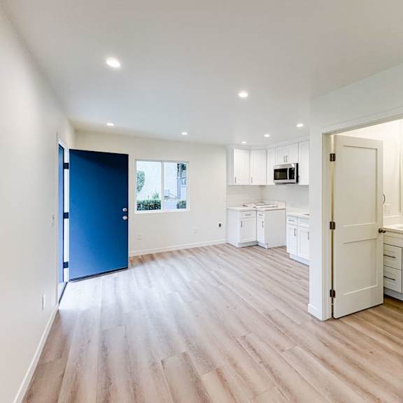 a kitchen with white cabinets and a blue door.