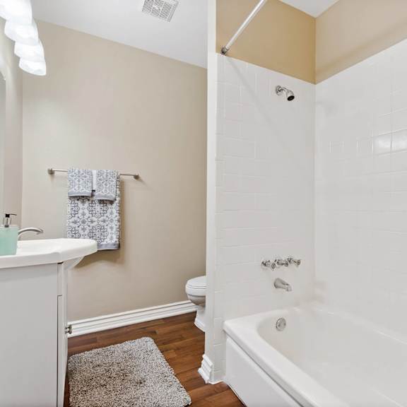 a bathroom with a white tub, sink and hardwood floors at terramonte apartment homes, california
