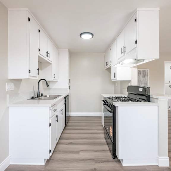 a white kitchen with a black stove top oven.