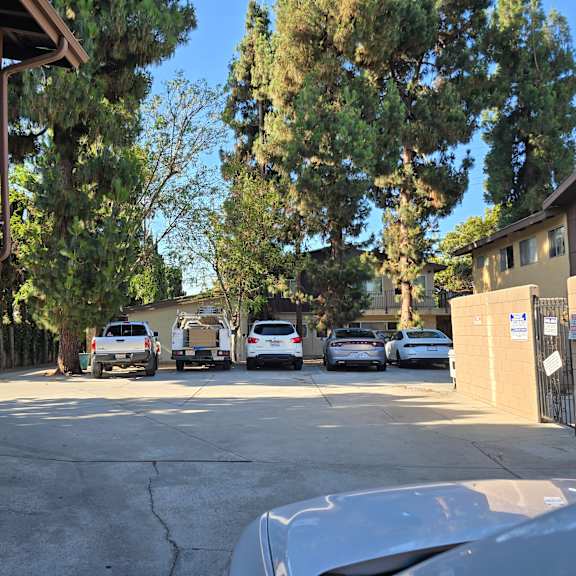 a parking lot with cars and a building with an air conditioning unit.