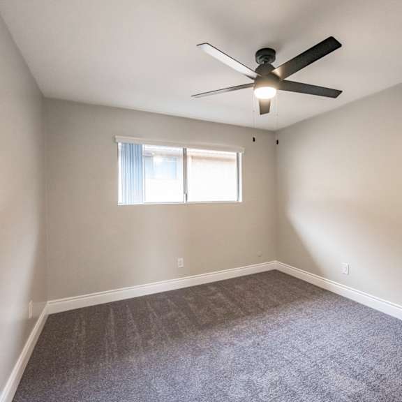 a room with a ceiling fan and a window.