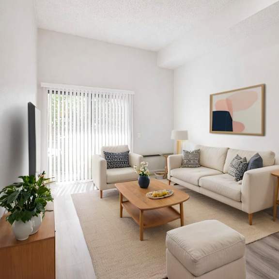 a living room with a white couch, a wooden coffee table, and a potted plant.