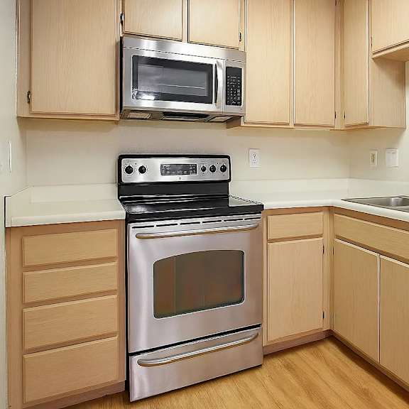 a kitchen with wooden cabinets and a stainless steel oven.
