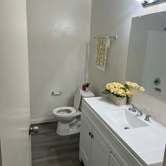 a white bathroom with a toilet, sink, and mirror.