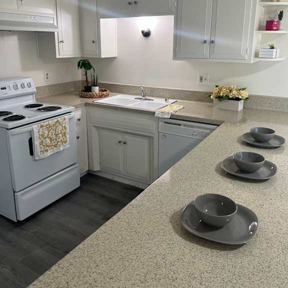 a kitchen with a white stove and grey cabinets.