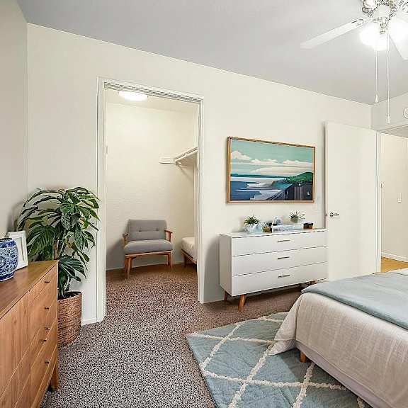 a bedroom with a bed, dresser, chair, and painting.
