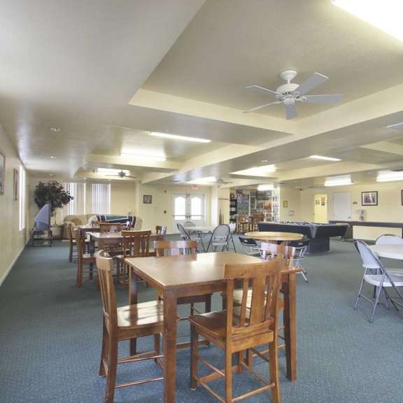 a room with tables and chairs and a ceiling fan.