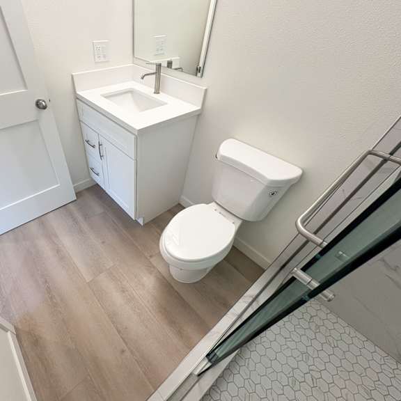 a white toilet sits in a bathroom next to a sink and a white cabinet.