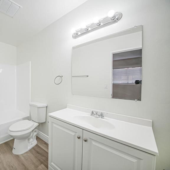 a white bathroom with a toilet, sink, and mirror.