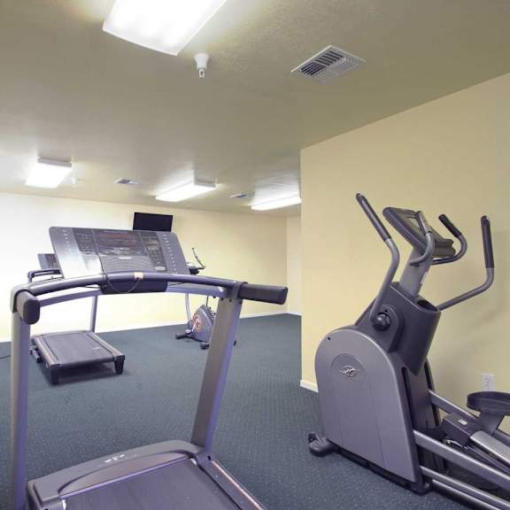 a gym room with a treadmill, elliptical trainer and a stationary bike.