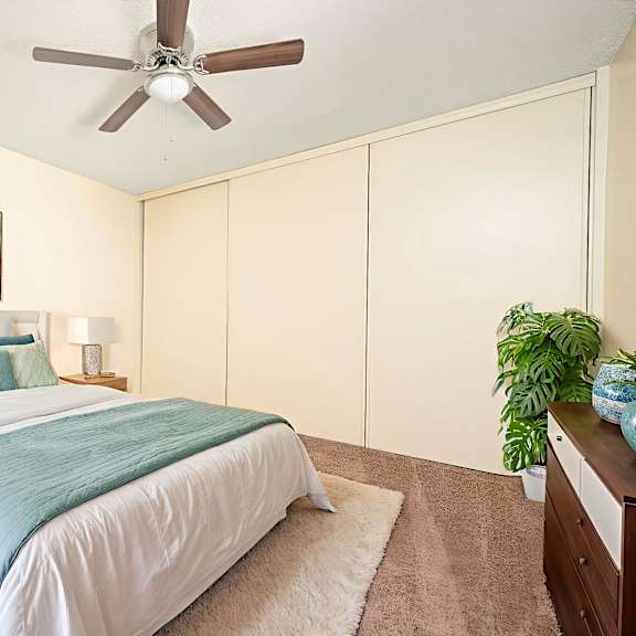 a bedroom with a bed, a ceiling fan, and a painting on the wall.