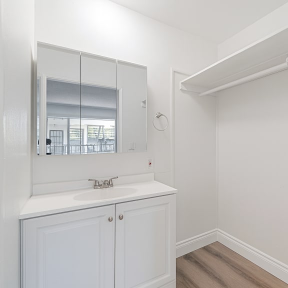 a white bathroom with a sink and mirror.