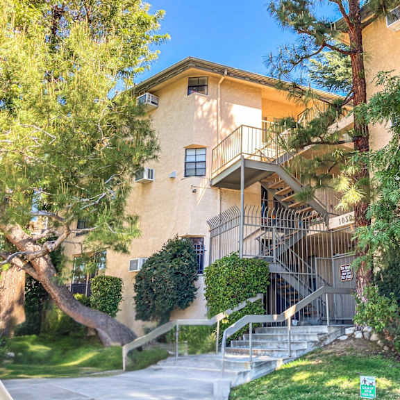 a building with a staircase and trees in front.