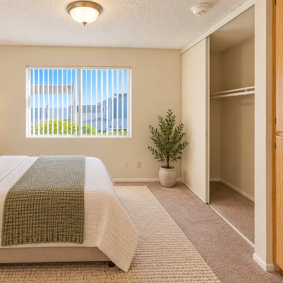 a bedroom with a large bed and a window with blinds.