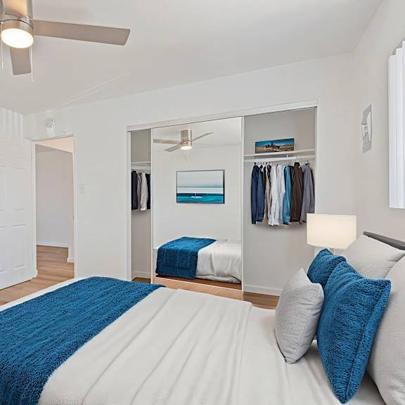 a bedroom with a bed, a dresser, a mirror, and a ceiling fan.
