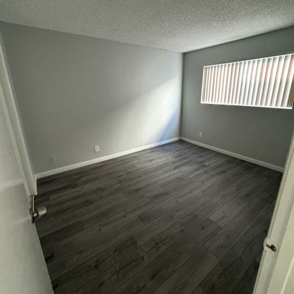 a room with wooden flooring and a window with blinds.