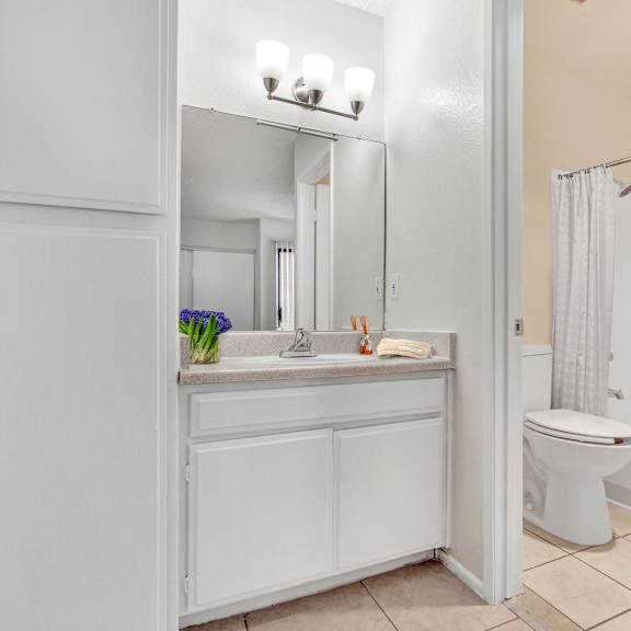 a white bathroom with a toilet, sink, and mirror.