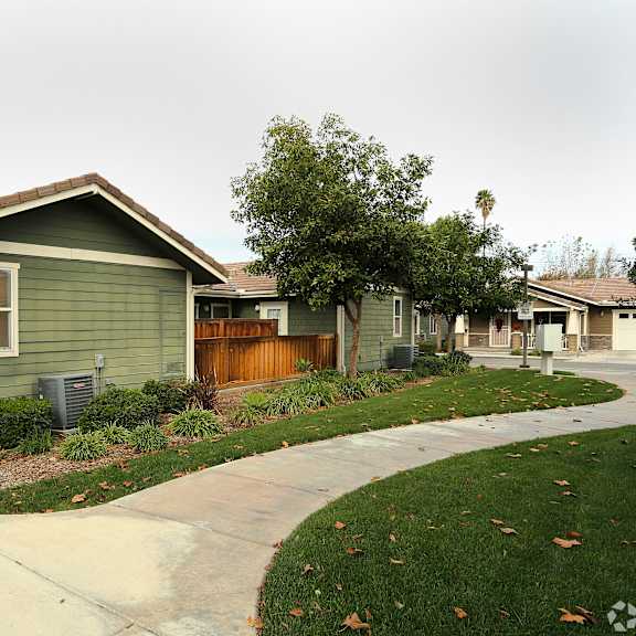 a green house with a brown fence and a grey roof.