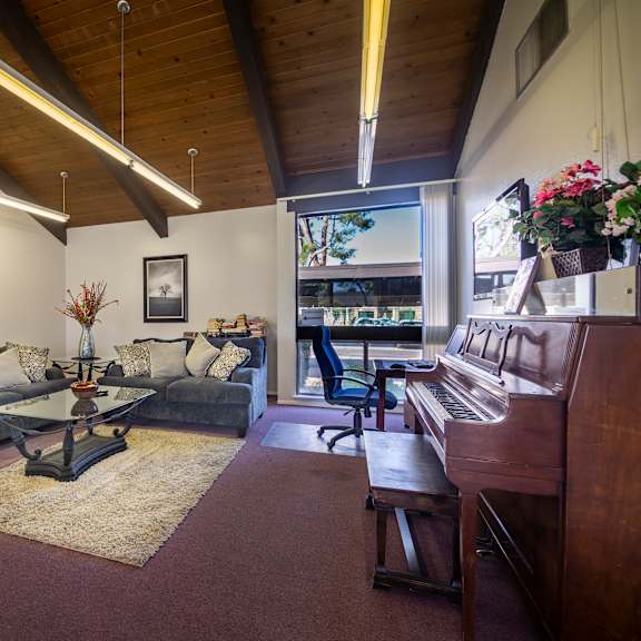 a living room with a couch, a coffee table, and a piano.