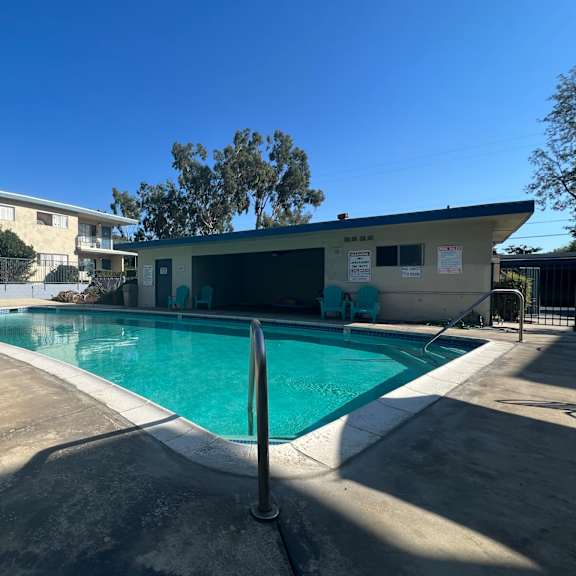 a swimming pool in front of a building with a blue sky in the background.