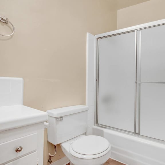 a white toilet sits next to a white cabinet in a bathroom.