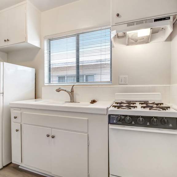 a small white kitchen with a refrigerator, sink, and stove.