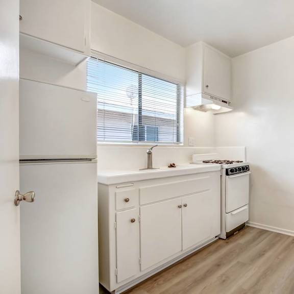 a small kitchen with white cabinets and a window.