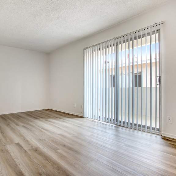 a room with wooden flooring and a window with blinds.