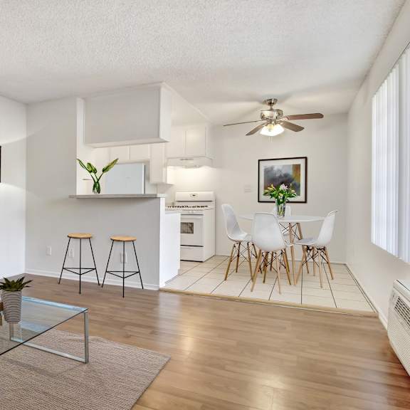 a living room with a grey sofa, a glass coffee table, and a bar area with stools.