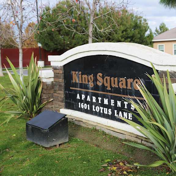 a sign for king square apartments stands in front of a building.