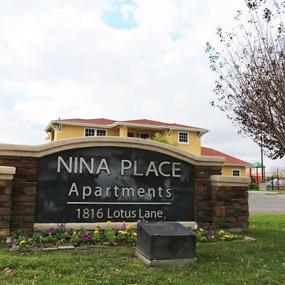 a sign for nina place apartments sits in front of a building.