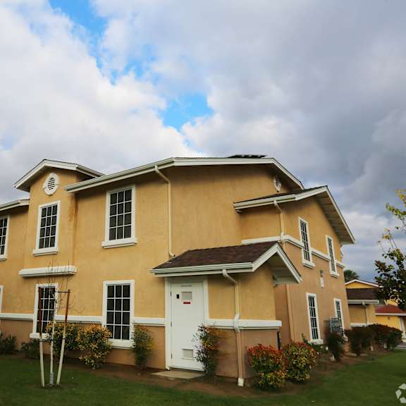 a yellow two-story house with a white door and windows.