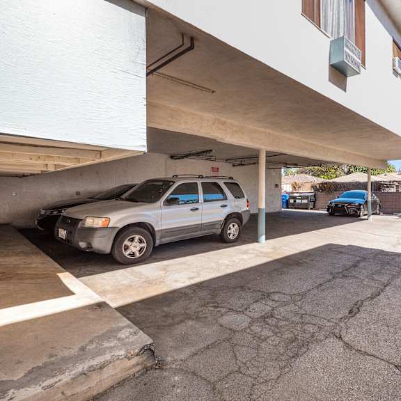 a silver car is parked in a garage under a white building.