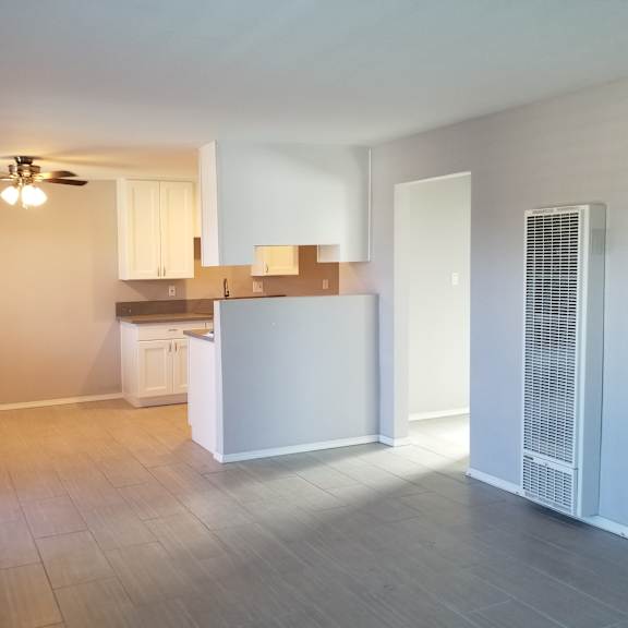 a room with a ceiling fan and a kitchenette.