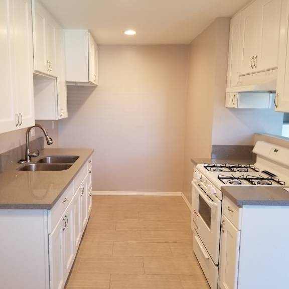 a kitchen with white cabinets and a stove top oven.