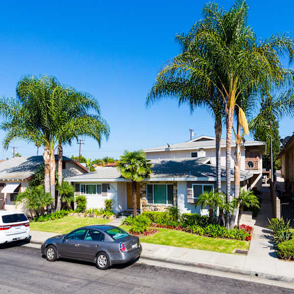a row of houses with cars parked in front.