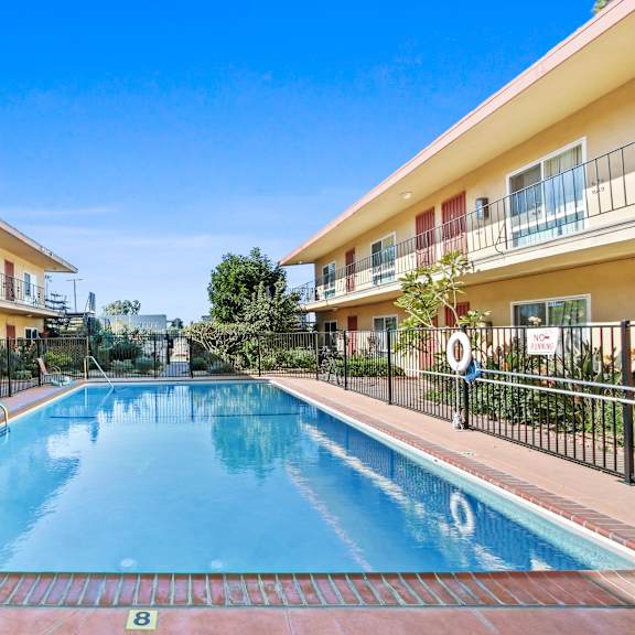 a swimming pool in front of a building with a red and white striped awning.