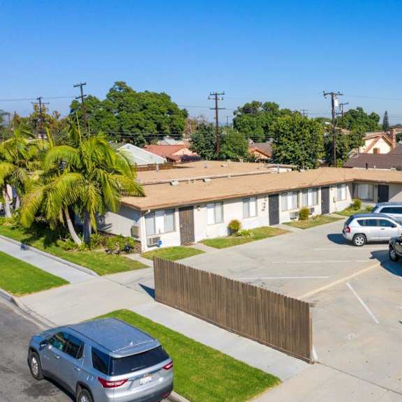 a row of houses with cars parked in front.