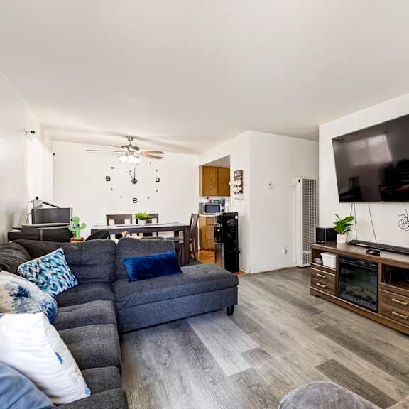 a living room with a grey couch and a television on a cabinet.