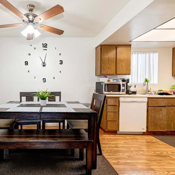 a dining room with a table set for two and a clock on the wall.