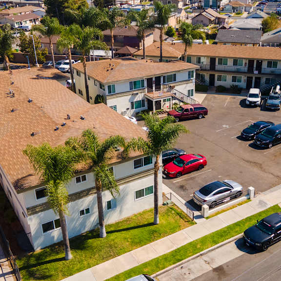 a parking lot with cars and a building with a red car parked in front.