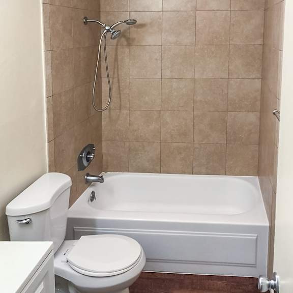 a white toilet sits next to a white bathtub in a bathroom.