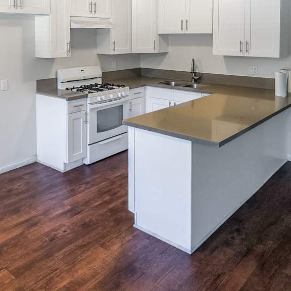 a kitchen with white cabinets and a wooden floor.