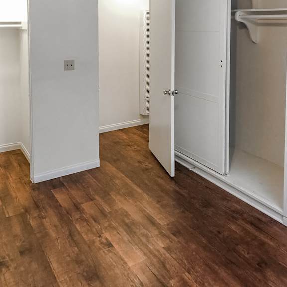 a white door is open to a room with wood flooring.