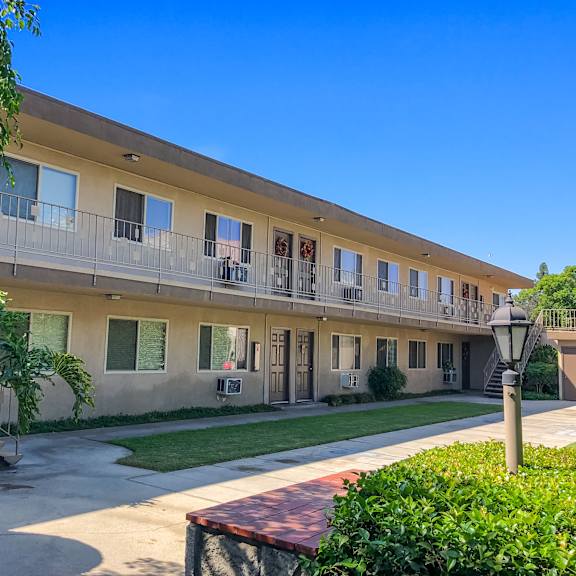 a sunny day at the apartment complex with greenery and clear skies.
