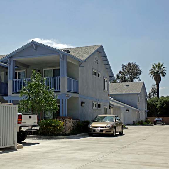 a white car is parked in front of a two-story house.
