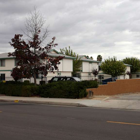 a white building with a green roof is surrounded by a black fence.