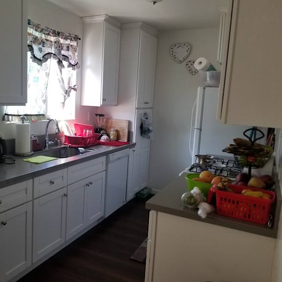 a kitchen with white cabinets and a counter with a basket of fruit on it.