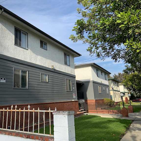a grey house with a white fence in front.